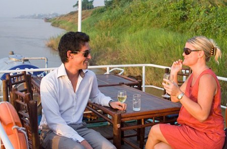 Tourists enjoy the drink on the deck of the boat