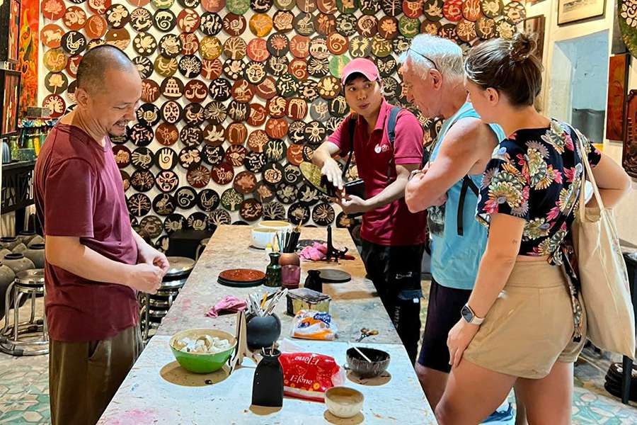 Artisan explaining a handcrafted object to visitors inside a workshop