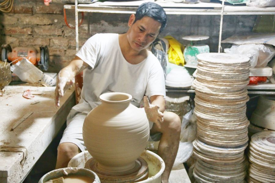 Artisan shaping a clay vessel at a pottery wheel in Bat Trang