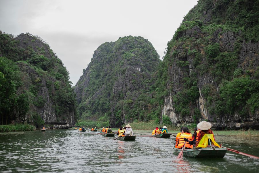 Rowboat travelling between limestone cliffs in Trang An, Ninh Binh