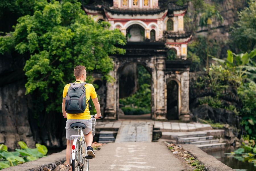 tourist cycling towards historic temple in ninh binh